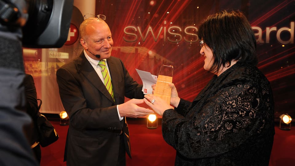 SRG SSR-Generaldirektor Roger de Weck übergibt der «Heldin des Alltags» Karin Boss-Röthlisberger den Pokal.