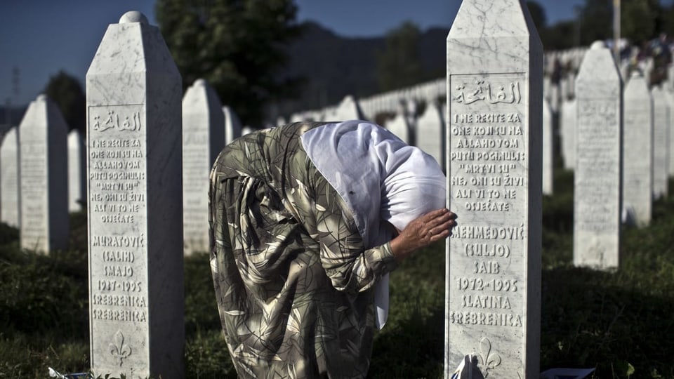 Frau trauert an Gedenktafeln bei Srebrenica