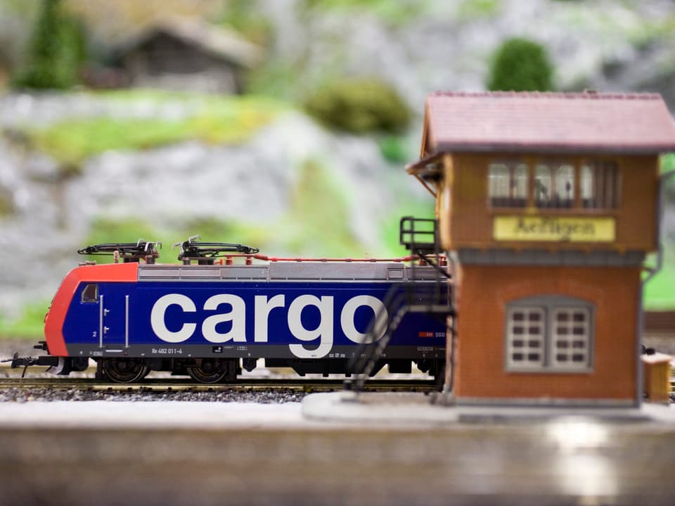 SBB-Cargo Lokomotive hinter einem hölzernen Stellewerkhaus auf einer Modellanlage