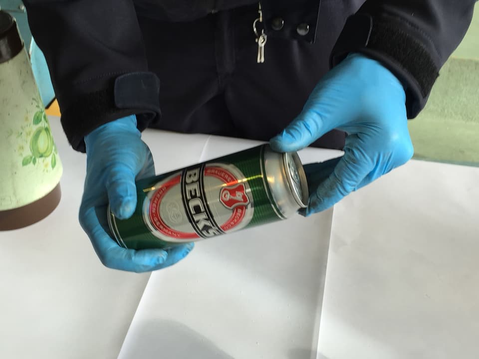 Ein Grenzwächter hält eine verschlossene Dose Bier in den Händen. 