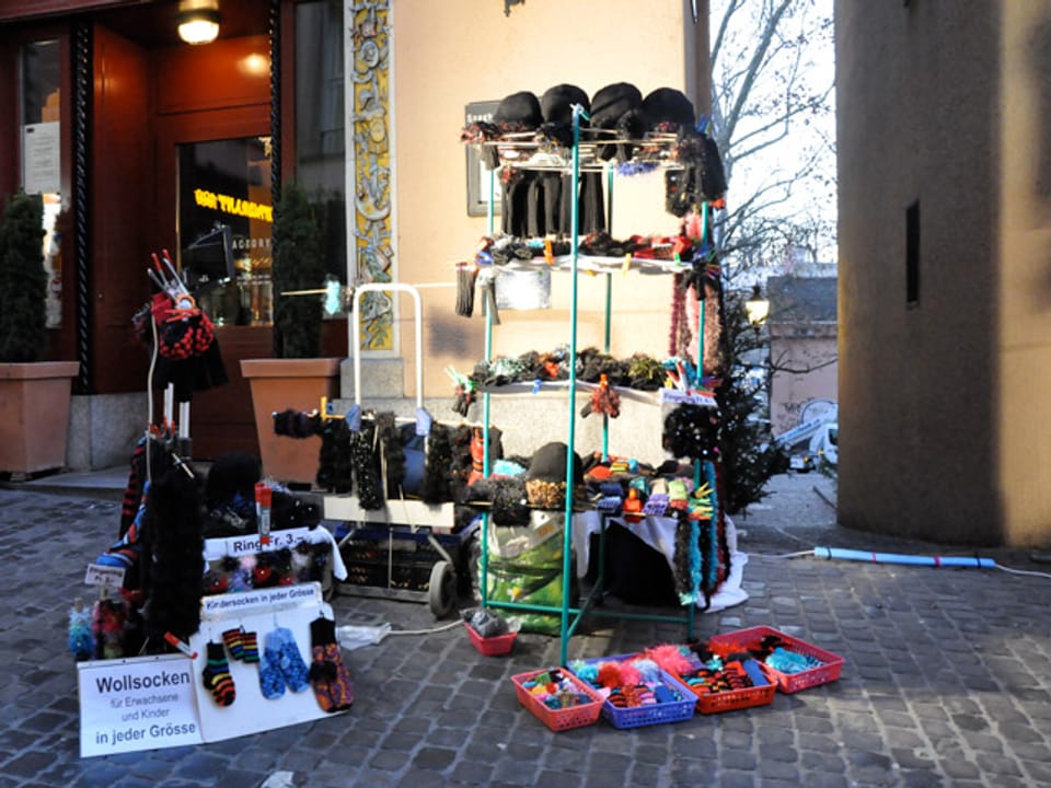 Auf der Strasse steht ein Gestellt mit Mützen und anderen Verkaufsartikeln