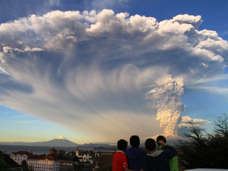 Eine Gruppe bestaunt die Aschewolke über einem Vulkan.