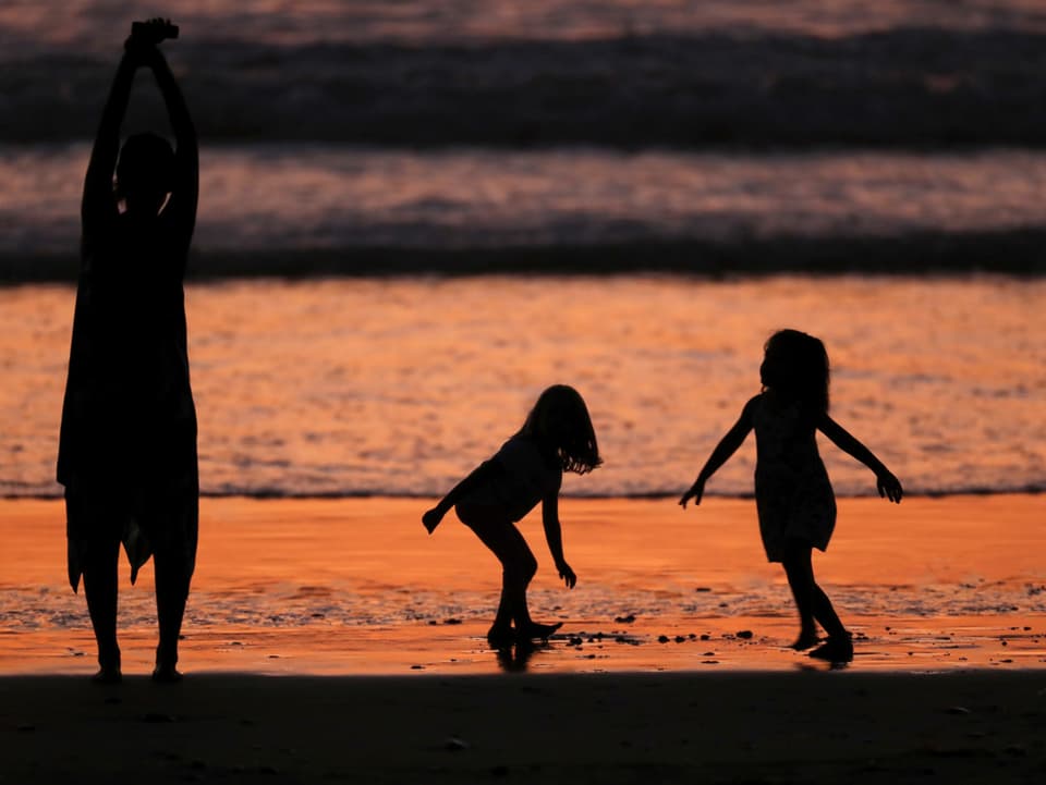 Familie am Strand bei Sonnenuntergang.