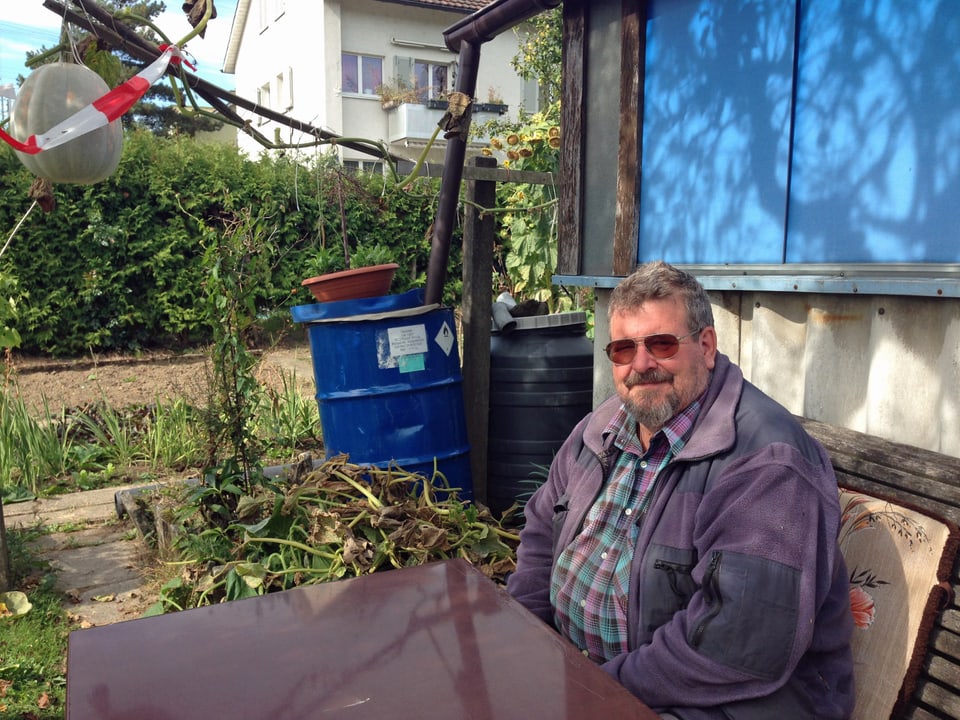 Heinz Nauer sitzt an seinem Gartentisch vor seiner Gartenparzelle. 