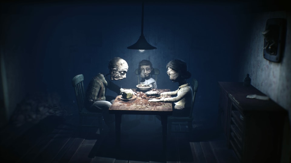 Eine gruselige Horror-Puppen-Familie sitzt bei einem düsteren Abendmahl zusammen.