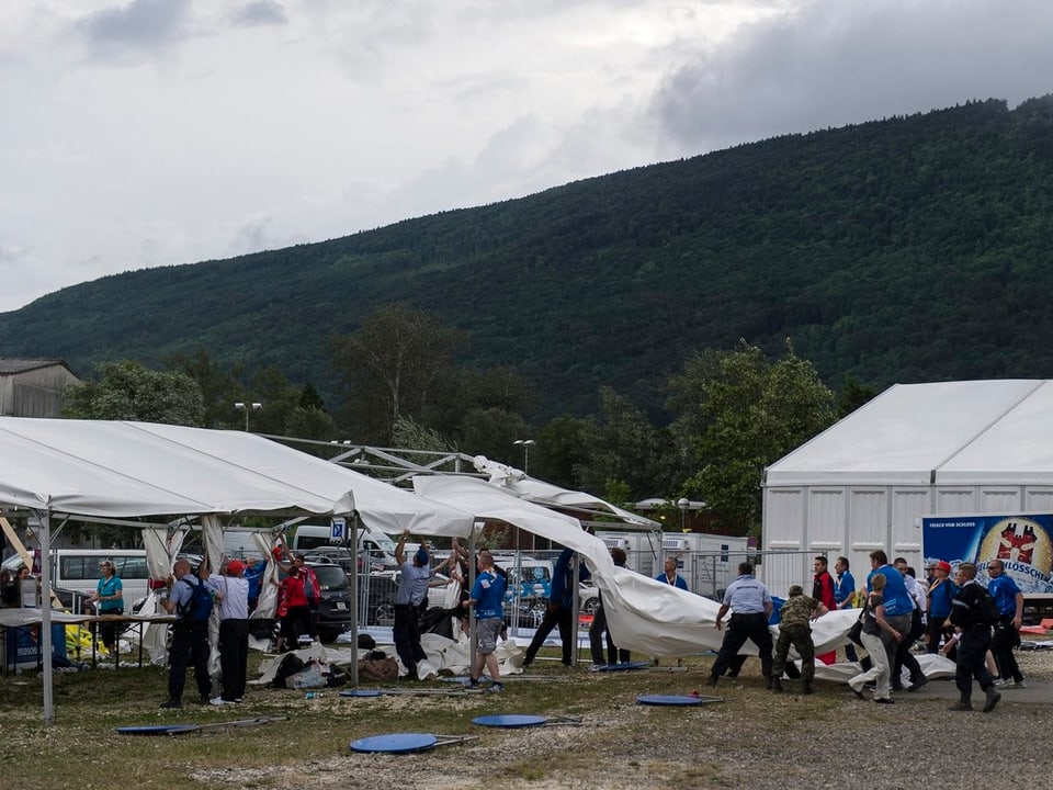 Besucher des Eidgenössischen Turnfestes halten Zeltstangen fest, um sie vor dem Davonwinden zu bewahren.