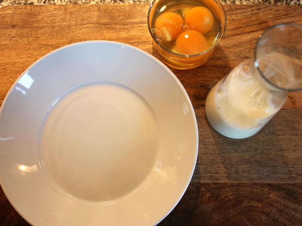 Eier und Milch neben Teller.