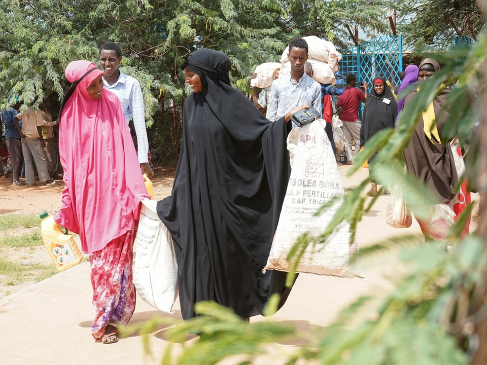 Frauen in bunter Kleidung tragen Säcke im Flüchtlingslager Dadaab in Kenia.