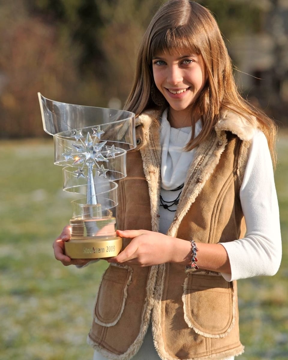 Eine junge Frau zeigt einen gläsernen Pokal.