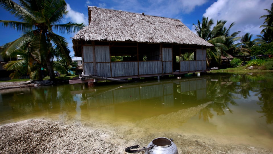 Ein verlassenes Haus, das bei Flut vom Meerwasser getroffen wird, in Kiribati.
