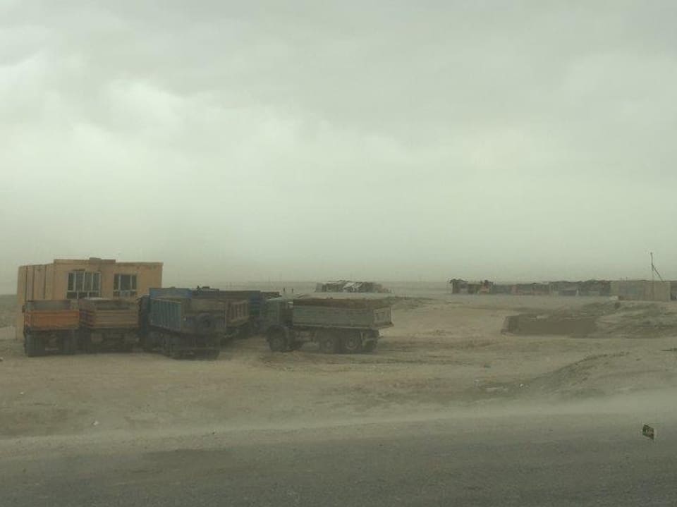 Herumstehende Lastwagen in einer Wüstenlandschaft in Grenznähe. 
