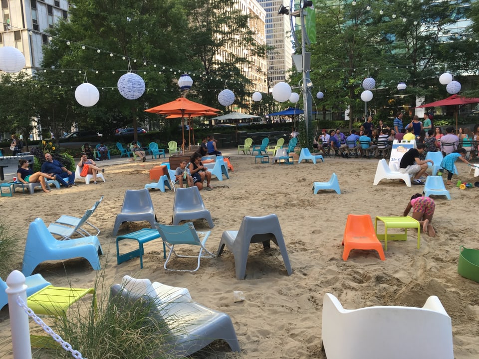 Farbige Plastikstühle auf einem Sandstrand mitten in der Detroiter Innenstadt.