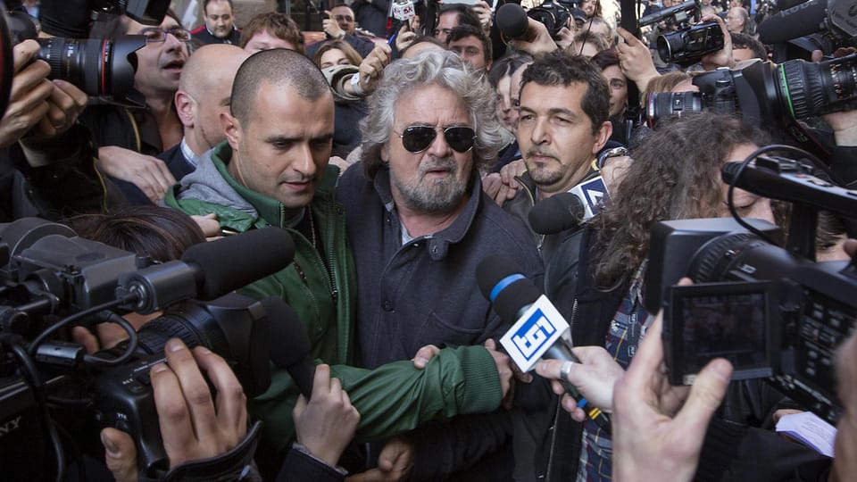 Beppe Grillo inmitten von Reportern.