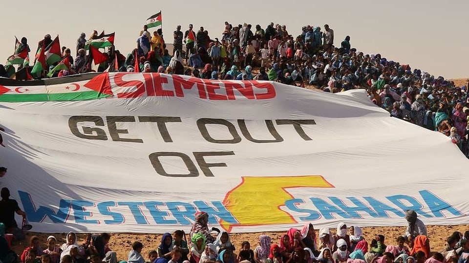 Protestierende und Transparent mit der Aufschrift "Siemens get out of Western Sahara"