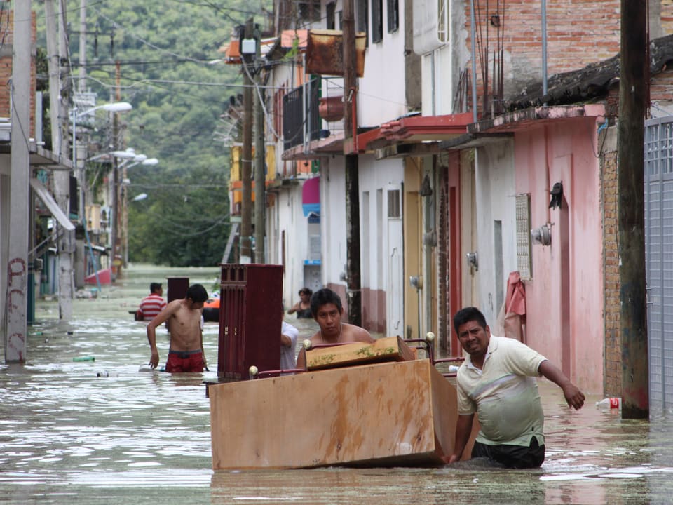 In einer überluteten Strasse packen Mexikaner Kisten