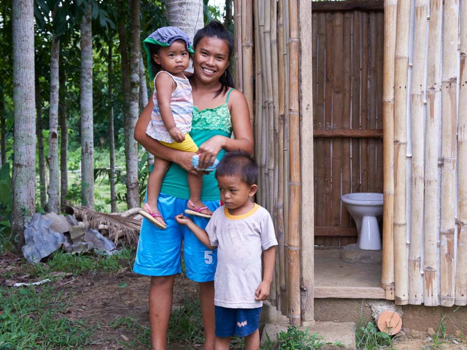 Frau mit zwei Kindern vor einer neuen Toilette