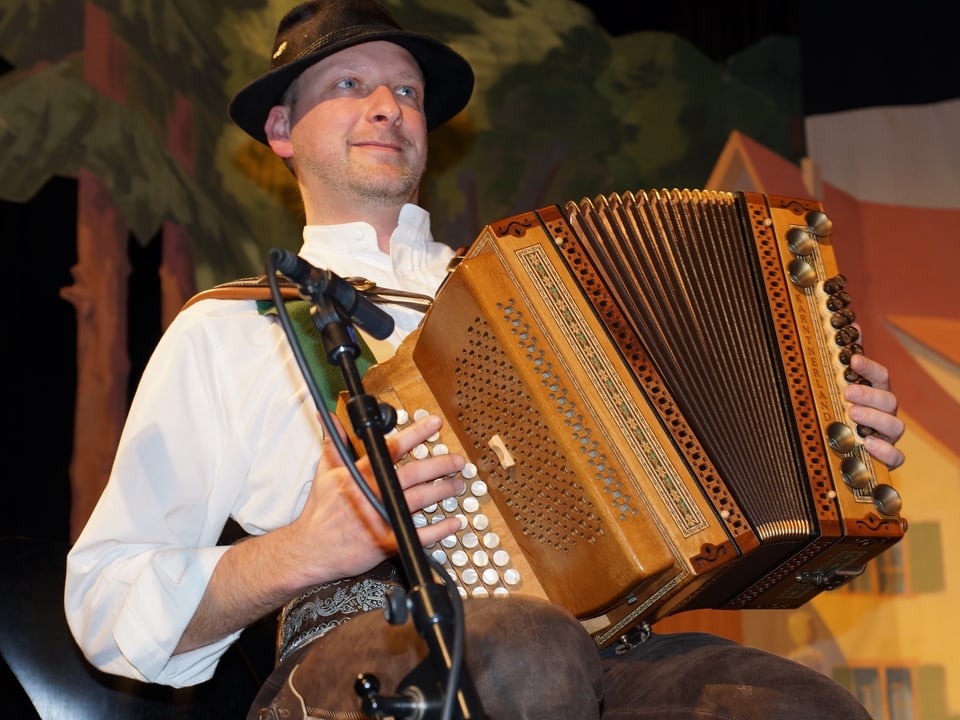 Ein Mann mit Filzhut spielt Harmonika.
