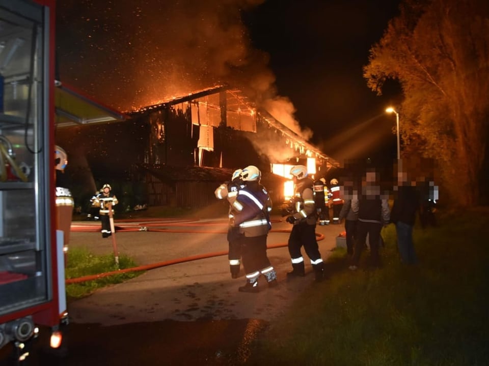 Feuerwehrleute vor brennendem Haus