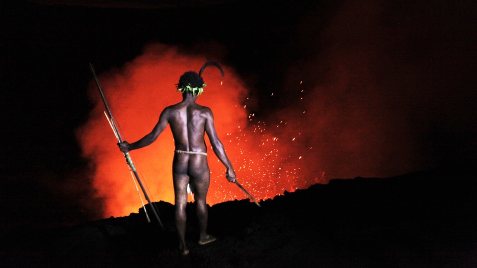 Mann steht vor ausbrechendem Vulkan.
