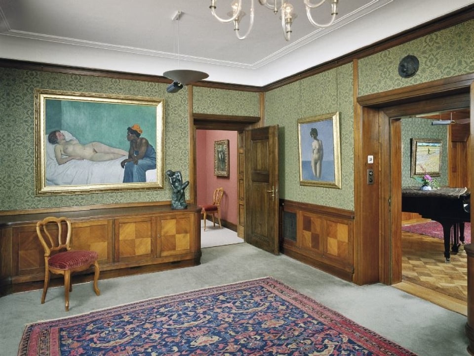 Ein Museumsraum mit grünen Wänden und Teppich.
