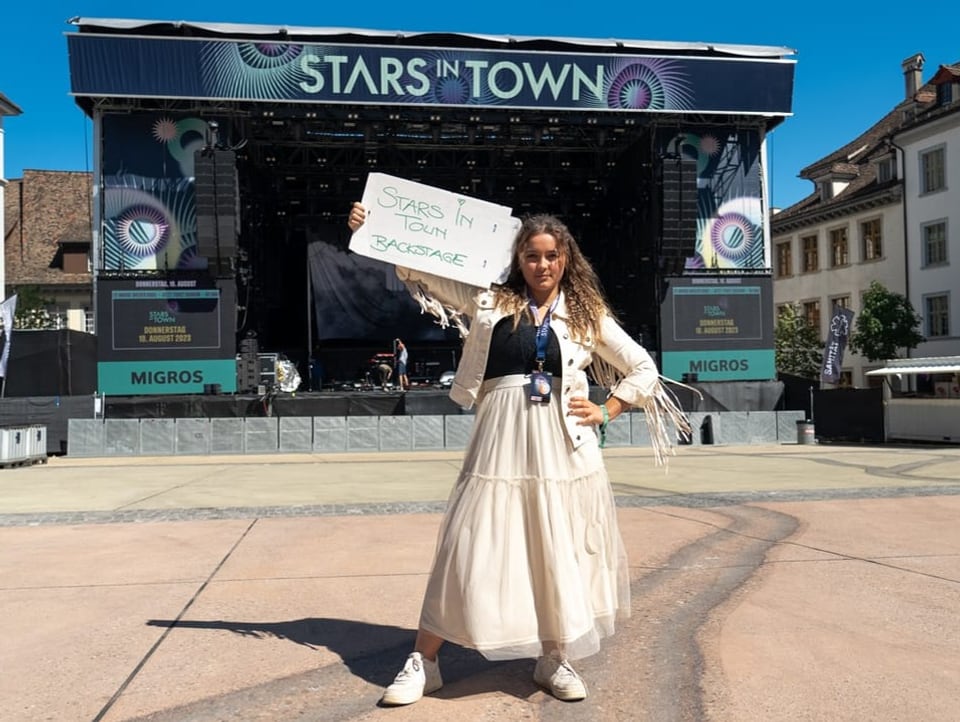 Sängerin steht mit einem Plakat vor der leeren Bühne am Stars in Town.