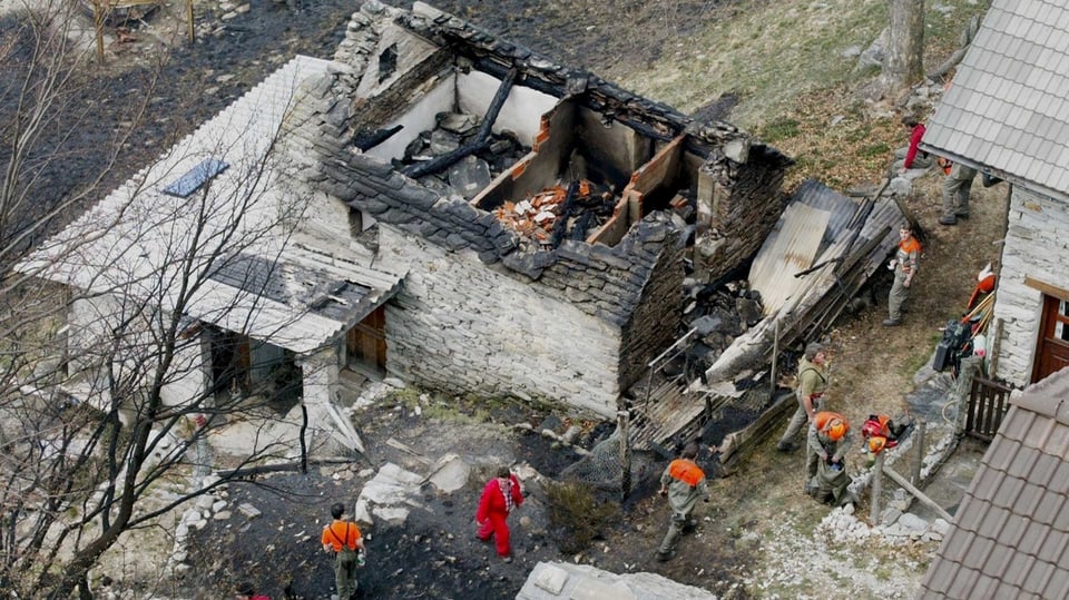 Aufnahme eines zerstörten Rusticos mit Feuerwehrleuten vor Ort