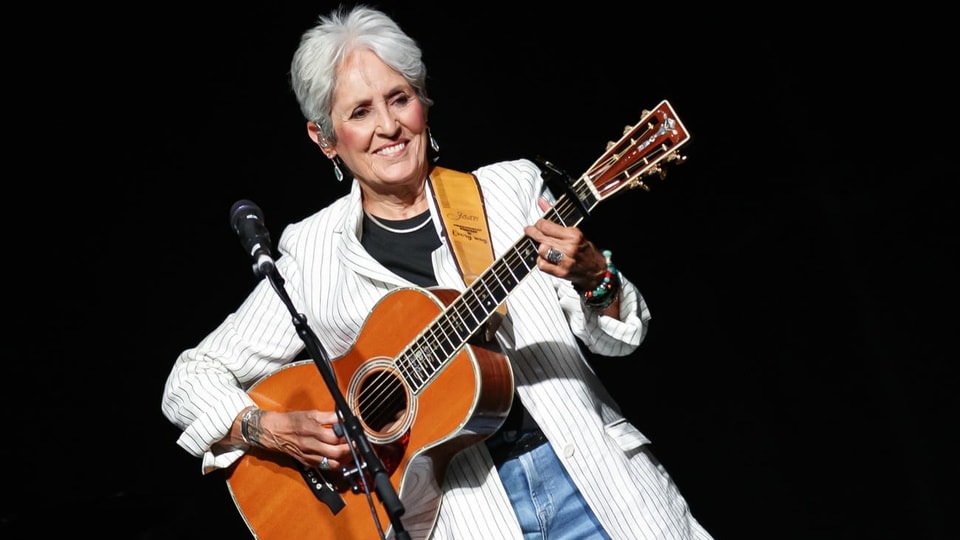 Frau mit kurzen grauen Haaren und Gitarre auf einer Bühne 
