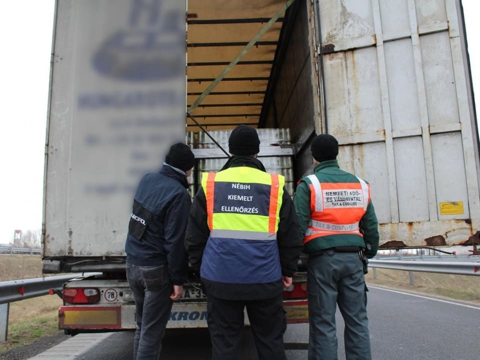 Polizisten schauen in den Laderaum eines Lastwagens.