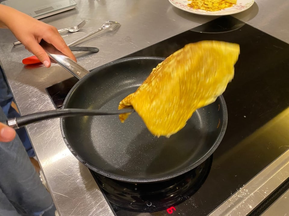 Eine Crèpe wird in der Pfanne gedreht.