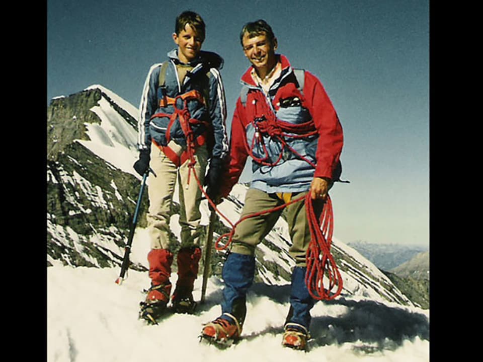 Adrian Küpfer steht mit seinem Vater auf einem schneebedeckten Berggipfel.