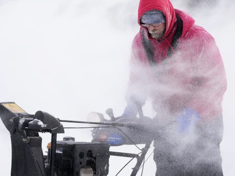 Ein Mann räumt Schnee mit einer Maschine