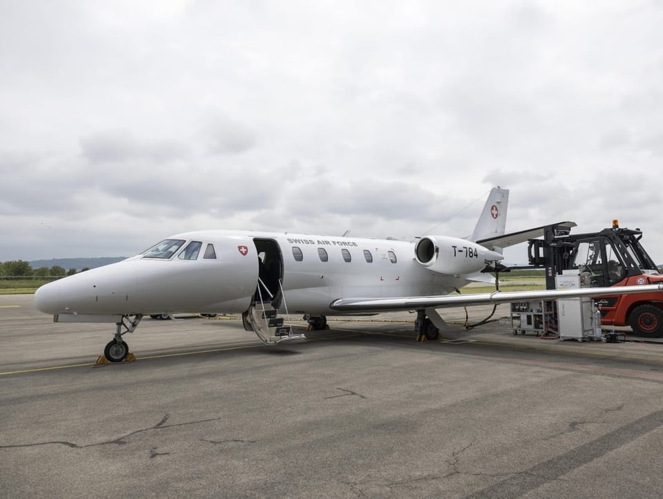 Ein Business-Jet der Schweizer Luftwaffe steht auf einem Rollfeld. Daneben stehen technische Geräte.