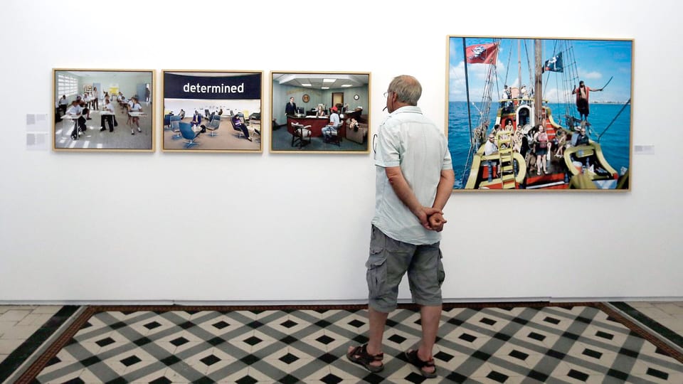 Ein Mann betrachtet Fotos in einer Ausstellung.