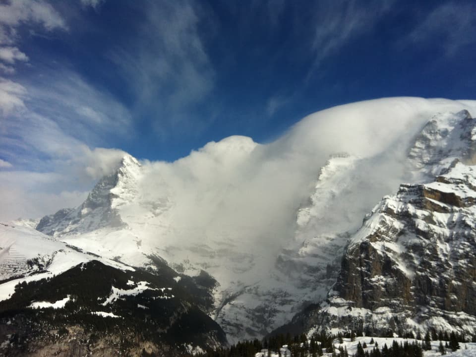 Blick auf die Jungfrauregion. Von der einen Seite drückt eine Wolkenwand heran, auf der anderen Seite stürzt die Luft ins Tal, die Wolke löst sich auf. 