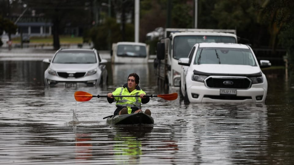 Mann mit Kanu auf überschwemmter Strasse