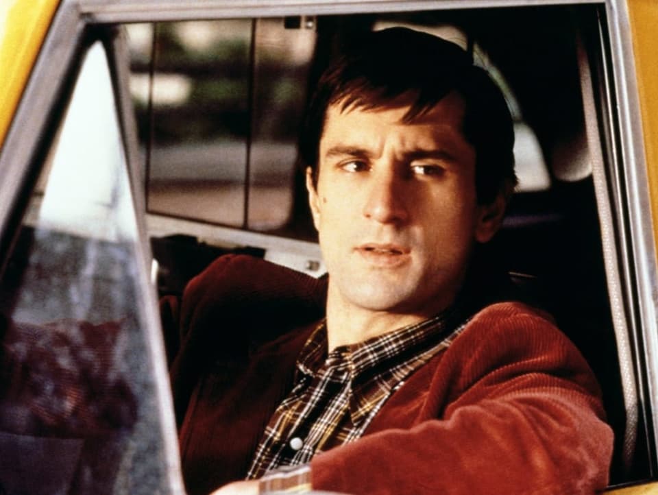 Robert De Niro sitzt im Taxi und schaut aus dem Fenster raus, den Unterarm lässig abgestützt.