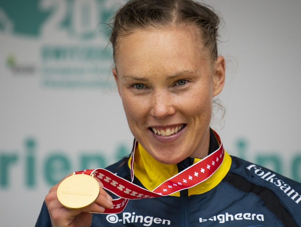 Tove Alexandersson zeigt ihre Goldmedaille in die Kamera.
