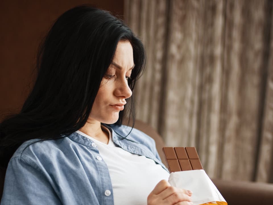 Auf dem Bild ist eine Frau zu sehen, die Schokolade isst.