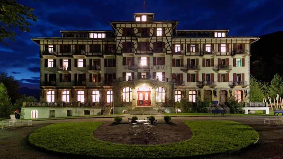 Die Frontansicht des Hotel mit leuchtenden Fenstern bei Nacht.