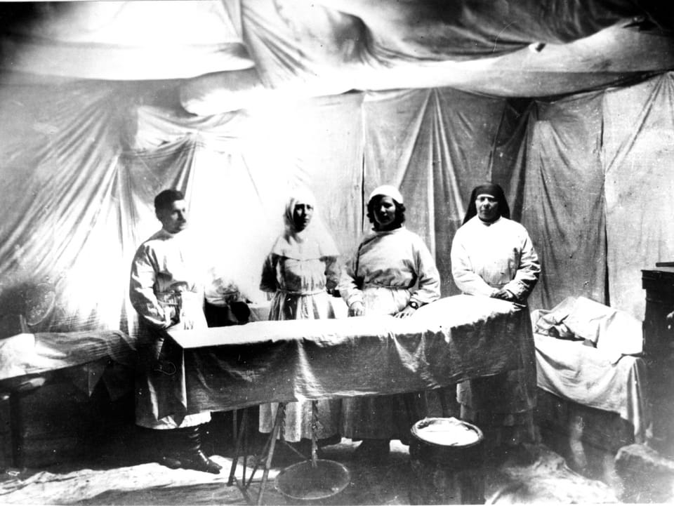Vier Mediziner (ein Mann und drei Frauen) vor einem Operationstisch.
