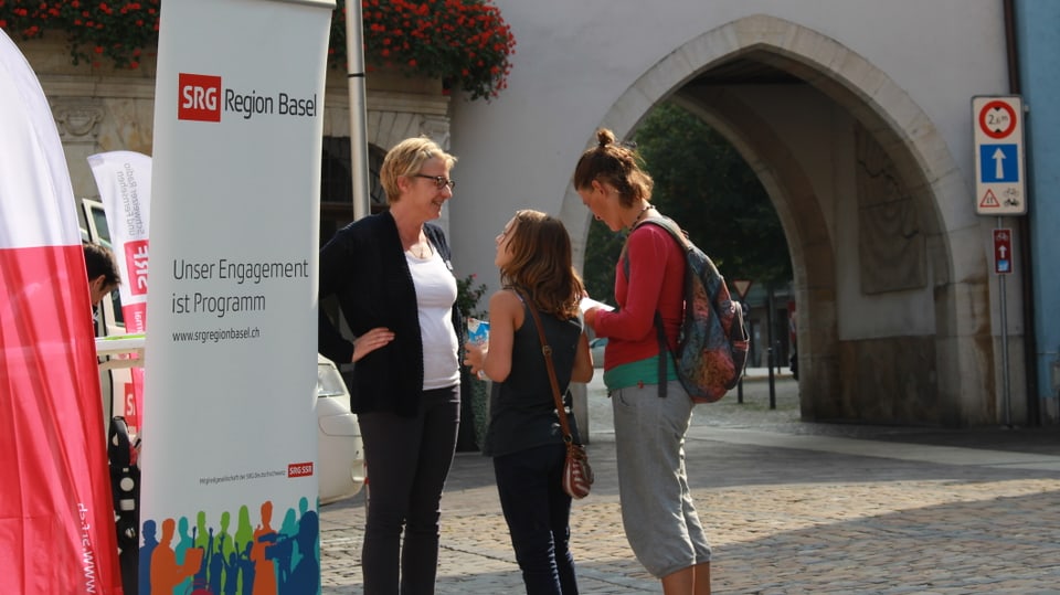 Sandra Rieder von der SRG Region Basel spricht mit zwei jungen Frauen vor dem Laufner Törli.
