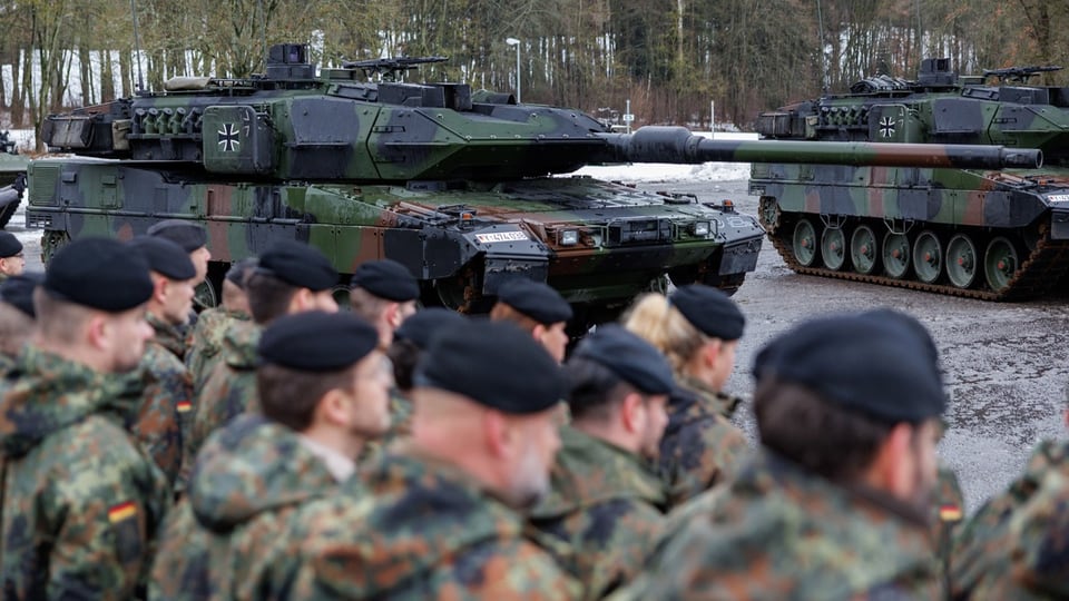 Bundeswehrsoldaten in Uniform vor geparkten Militärpanzern.