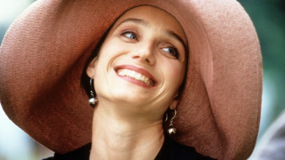 Junge Frau mit grossrandigem Hut und breitem Lächeln. 