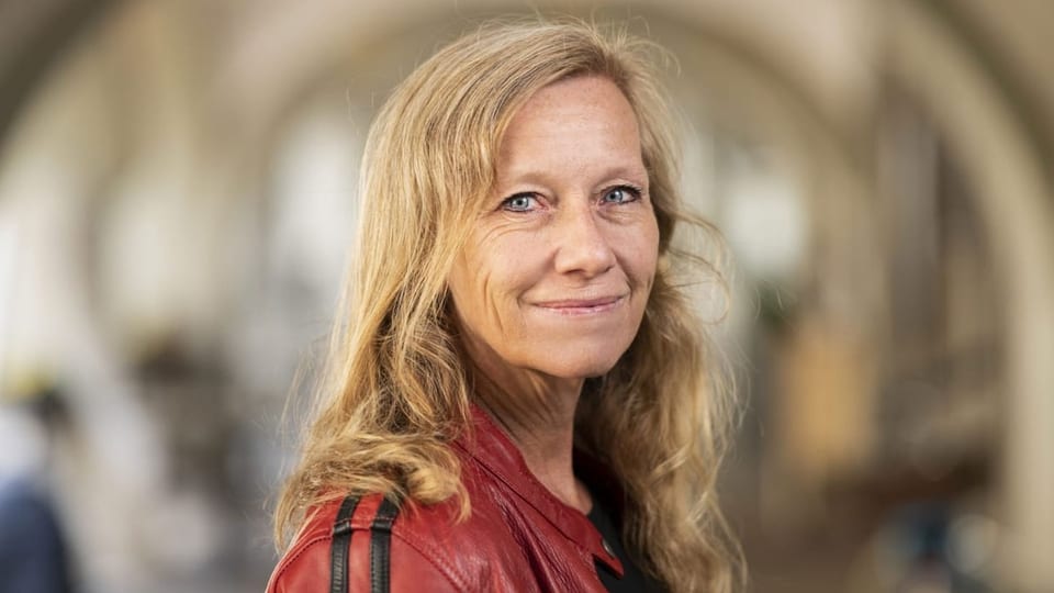 Eine blonde Frau in roter Lederjacke.