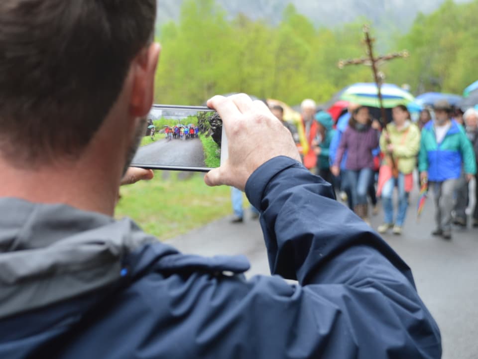 Nik Hartmann fotografiert mit seinem Telefon die Menge der Gläubigen auf der Prozession. 