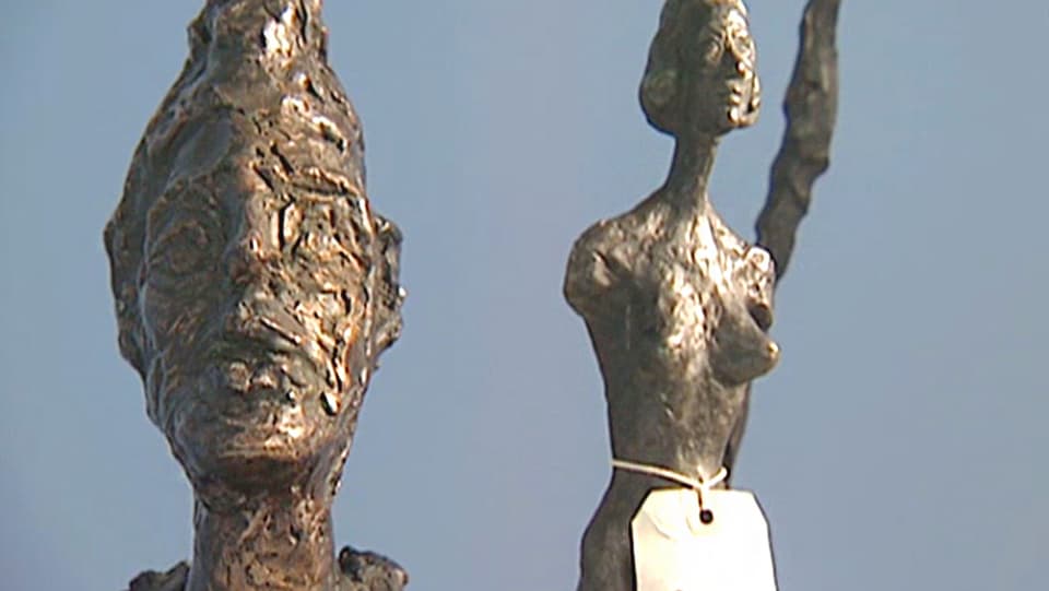 Zwei Skulpturen aus Metall: Ein Kopf und ein Frauenkörper. 