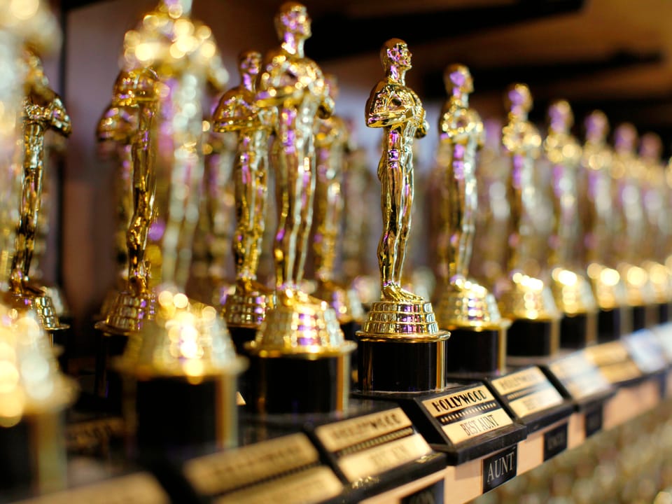 Goldene Oscar-Statuen nebeneinander aufgereiht in die Unschärfe verlaufend.