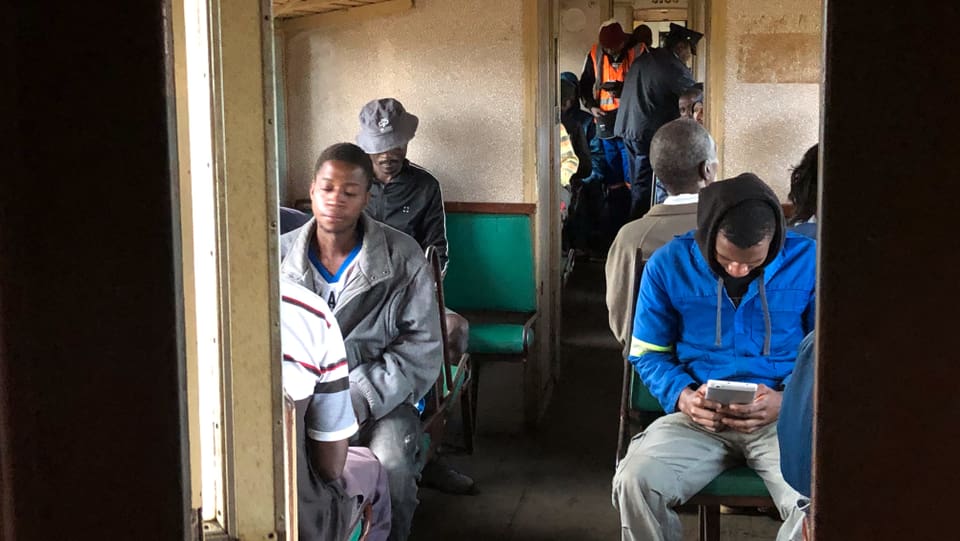 Blick in den Zugwaggon: Die Männer sitzen und starren in ihr Smartphone.