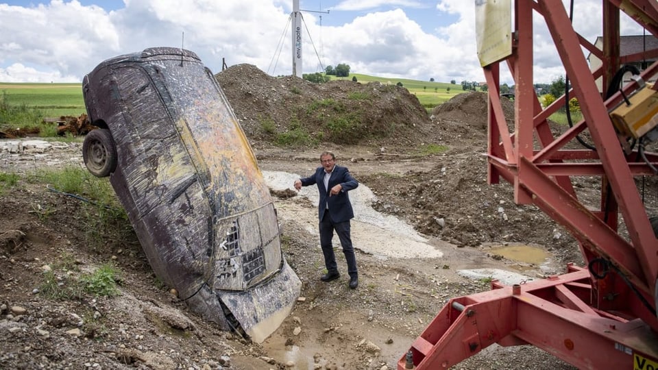 Mann steht neben eingegrabenem Auto-Wrack 