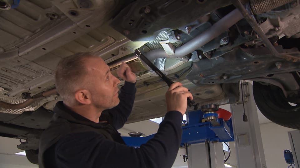 Mann untersucht das Auto von unten -
